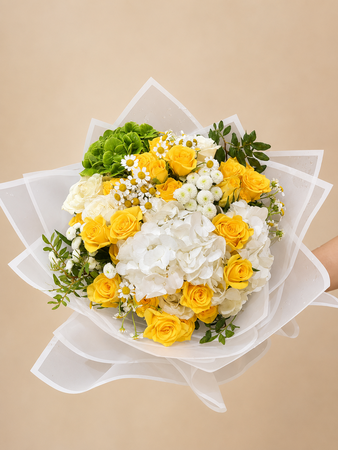 Luxury bouquet of yellow roses, white hydrangeas, green hydrangeas, and chamomile flowers wrapped in elegant white wrapping by Ishbelia Gardens Dubai