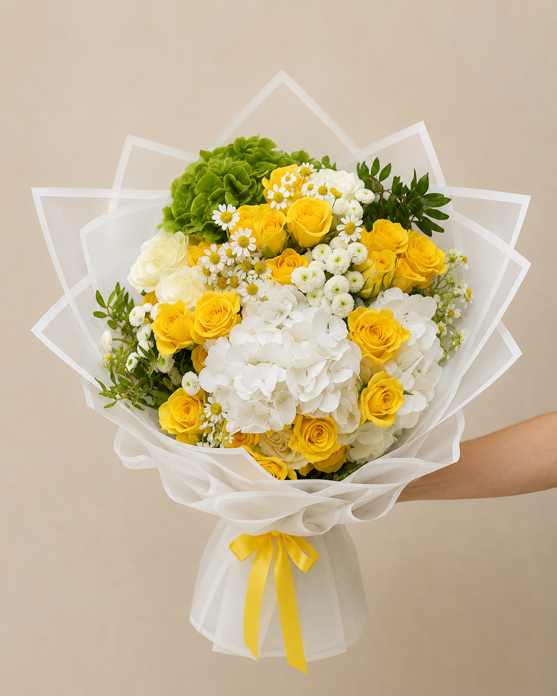 Luxury bouquet of yellow roses, white hydrangeas, green hydrangeas, and chamomile flowers wrapped in elegant white wrapping by Ishbelia Gardens Dubai.