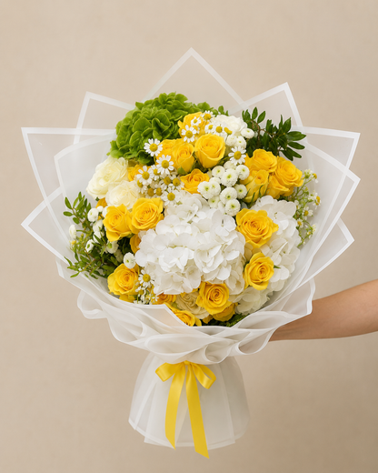 Luxury bouquet of yellow roses, white hydrangeas, green hydrangeas, and chamomile flowers wrapped in elegant white wrapping by Ishbelia Gardens Dubai.