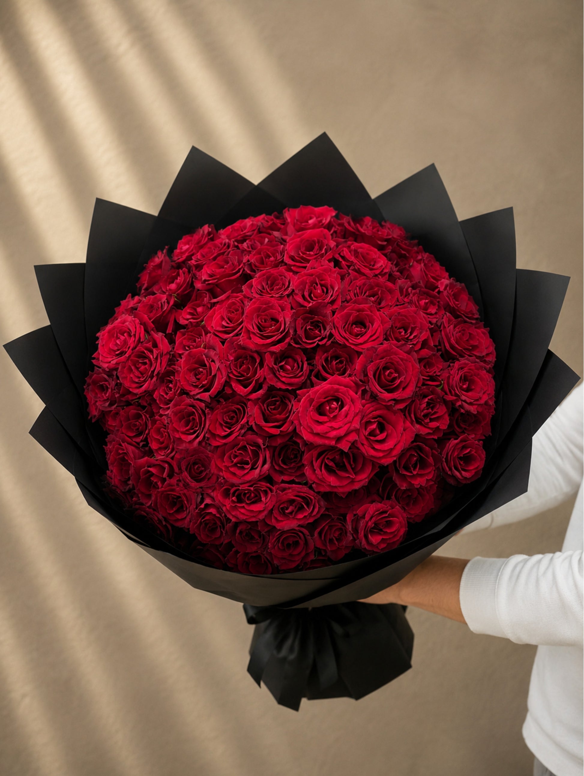 Luxury bouquet of 101 premium fresh red roses wrapped in elegant black paper by Ishbelia Gardens Dubai.