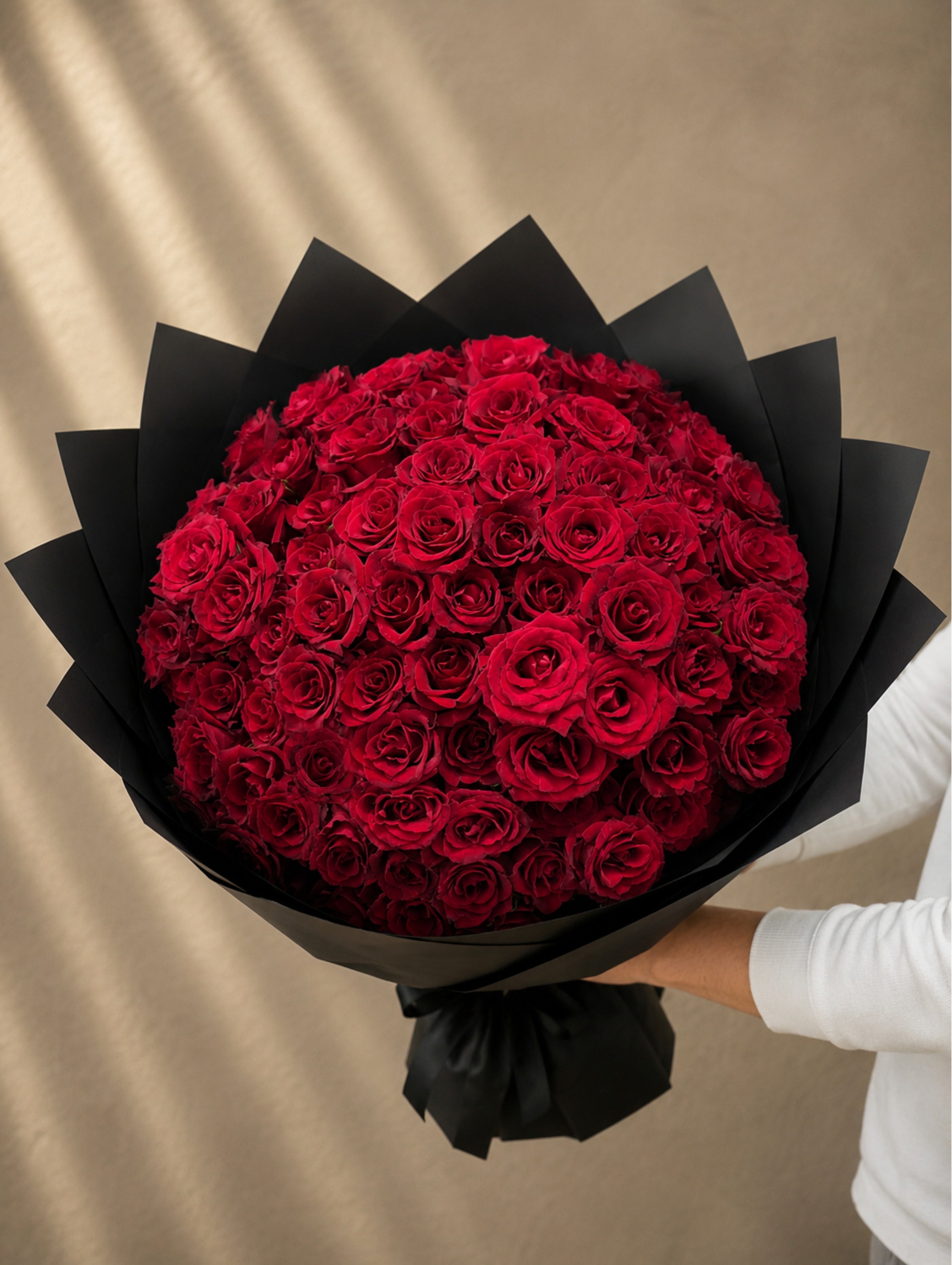 Luxury bouquet of 101 premium fresh red roses wrapped in elegant black paper by Ishbelia Gardens Dubai.