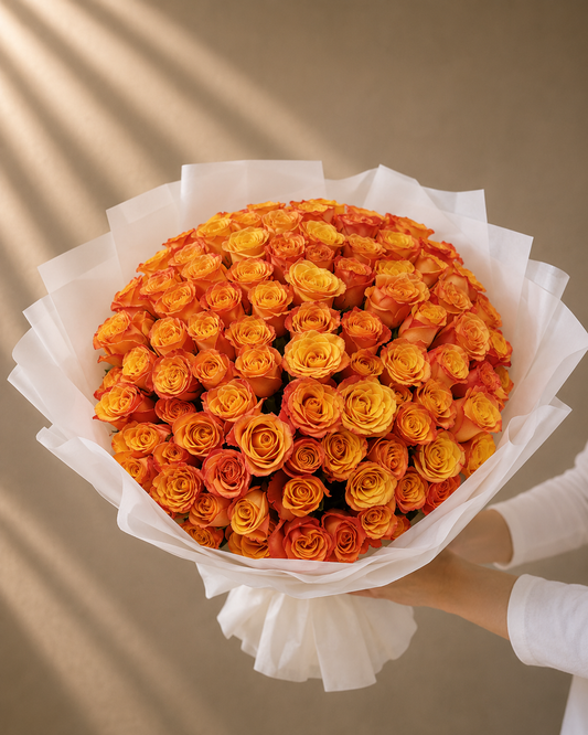 Luxury bouquet of 101 premium fresh orange roses wrapped in elegant white designer wrapping by Ishbelia Gardens Dubai.